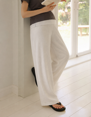Person wearing white pants and a brown top standing indoors.