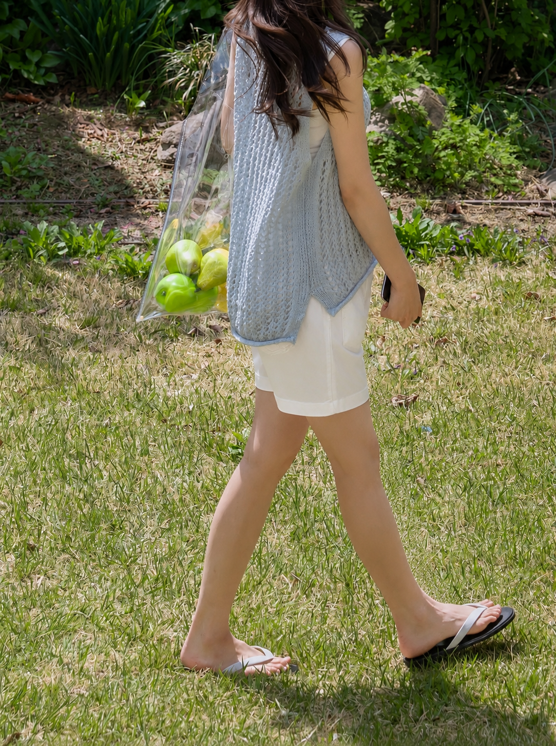 Person walking outdoors with a reusable bag full of apples