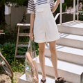 Woman standing on outdoor steps holding a coffee cup and a clear bag.