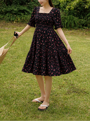 Woman in a black floral dress standing in a garden
