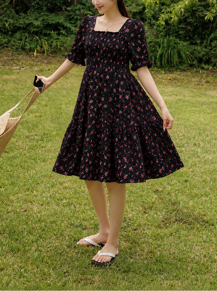 Woman in a black floral dress standing in a garden