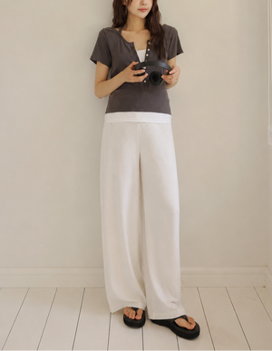 Woman standing in a minimalistic room holding a camera.