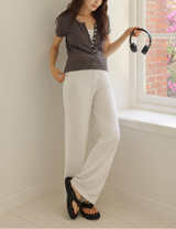 Woman holding headphones in a room with a window showing a garden view