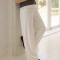 Person wearing white pants and a brown top standing indoors.